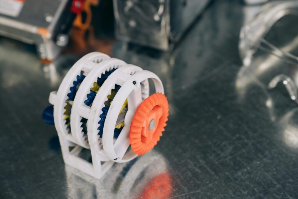 Close-up of a 3D printed gear mechanism with vibrant colors on a reflective metal surface.
